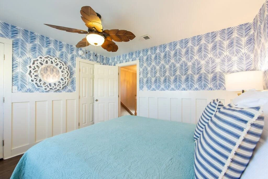 Bedroom with striped pillows and blue wallpaper, SouthWind West
